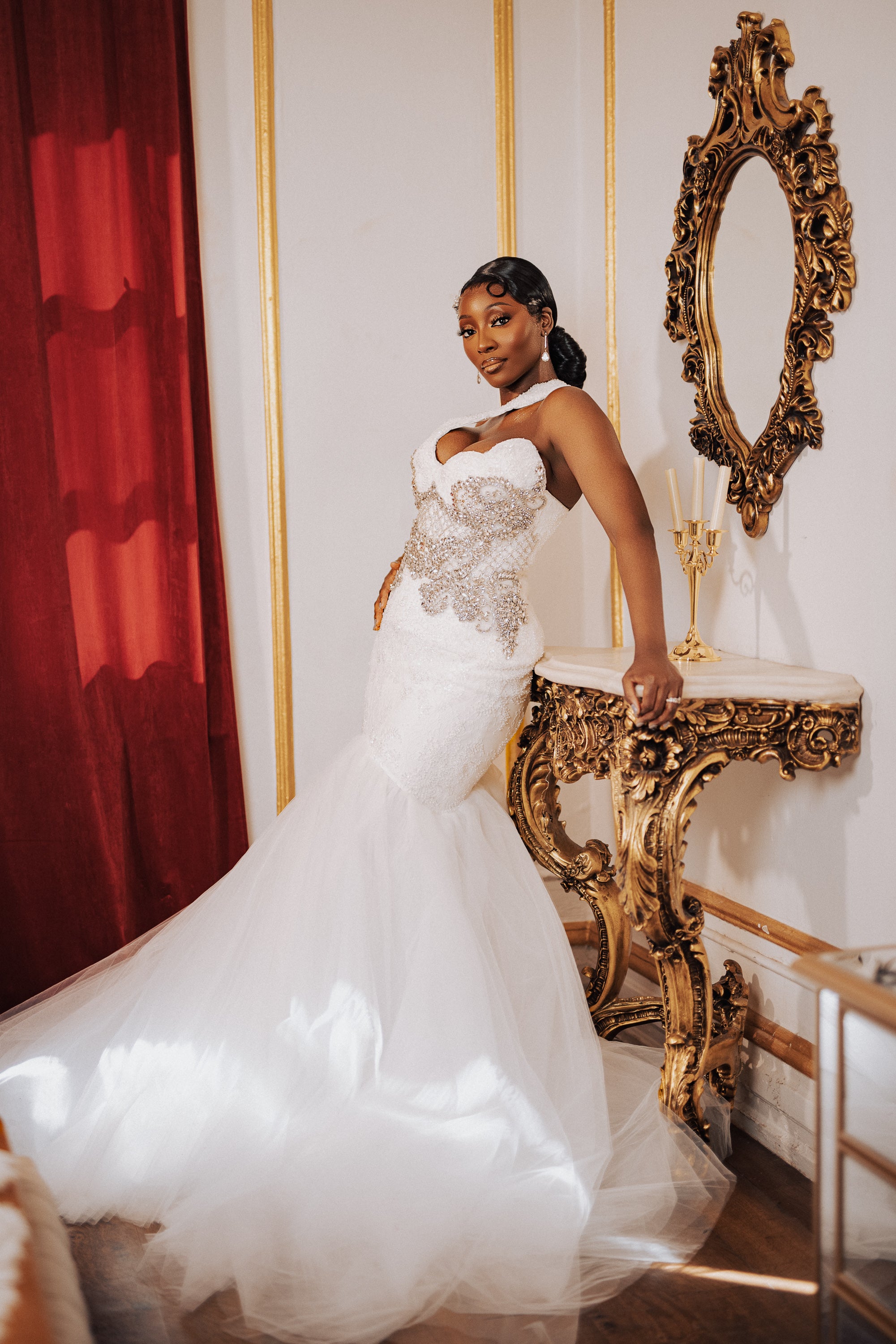 Luxury mermaid wedding gown with beaded bodice worn by a bride posing in a gold ornate bridal suite.